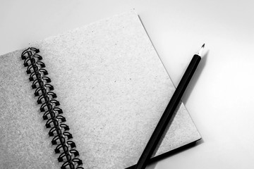 Top view of closed notebook with pencil on background.