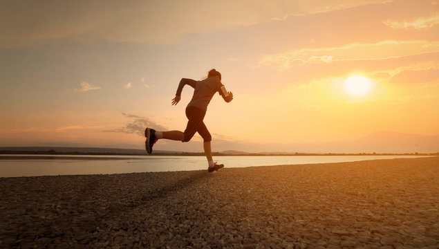 Woman running with sunset or sunrise background