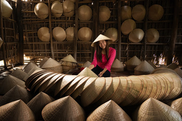 Asian traveler female craftsman making the traditional vietnam hat in the old traditional house in...