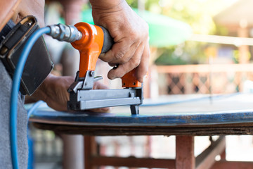 hand of a worker is using a nail gun