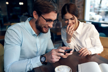 business colleagues are sitting in a cafe looking at the smartphone laughing