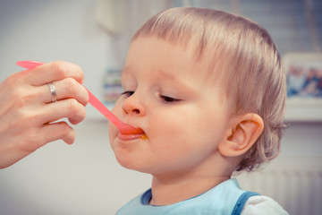 Little baby boy eating snack in preschool or nursery, dessert for kids concept