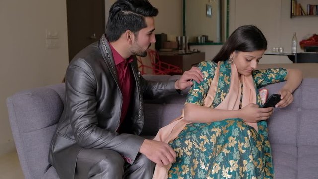 Indian husband tries to talk to his wife but she is busy with her addiction to her cellphone and glued to mobile and is unmoved at his requests and apologies as she doesn't care 