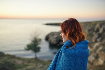 woman in a blanket looks at the evening sea nature