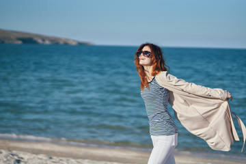 happy woman in glasses walks along the seashore nature