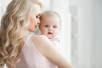 Young pretty mother with her little baby at home. Mom and daughter indoors.  month child with her...
