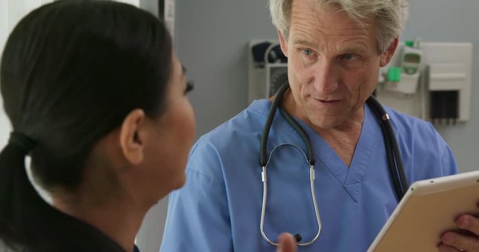 Senior doctor with tablet computer explaining treatment to patient in hospital