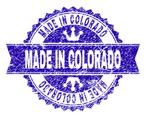 Obraz premium MADE IN COLORADO rosette stamp seal watermark with grunge style. Designed with round rosette, ribbon and small crowns. Blue vector rubber watermark of MADE IN COLORADO title with grunge style.