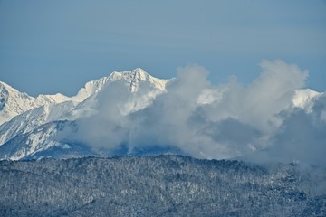 Panorama of snowy mountains. Winter forest and rocky peaks in the snow. Sunny winter day.