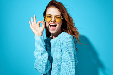 marks with fingers woman joyful in glasses on blue background