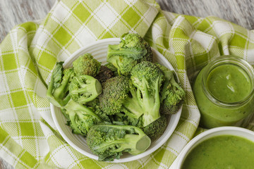 Fresh broccoli in the bowl, and portion of puree made from crushed broccoli, blurred background