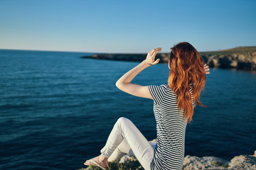 Fototapeta na wymiar woman sits on the bank straightens her hair looks at the sea