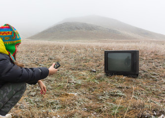 Girl on the nature lying on the ground and watching an old TV