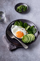 Fried eggs sided with avocado and spinach
