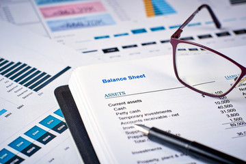 balance sheet, pen and glasses on the background of financial documents, close-up