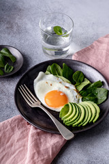 Obraz na płótnie Canvas Fried eggs sided with avocado and spinach