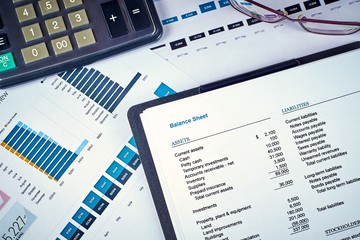 balance sheet, calculator and glasses on the background of financial documents, close-up