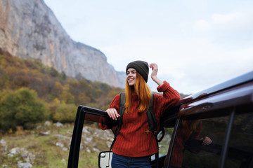 happy woman in nature looks out of the car mountains autumn