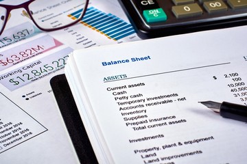 Naklejka na ściany i meble balance sheet, pen, calculator and glasses on the background of financial documents, close-up