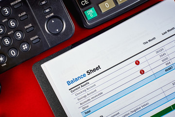 balance sheet, phone and calculator on a red velvet background, close-up