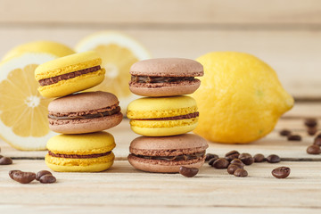 Yellow and brown french macarons with lemons and coffee beans on the wooden board
