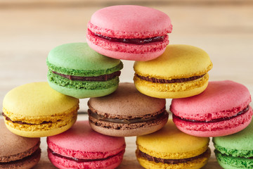 Fototapeta na wymiar Green, pink, yellow and brown french macarons on the wooden boards