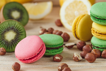 Green, pink, yellow and brown french macarons with lemon, kiwi and hazelnuts
