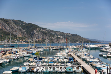 Fototapeta na wymiar Menton France July 9th 2015 : Yachts and small sailing boats moored in Menton harbour on a beautifulsummer day
