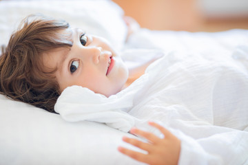 Adorable little girl lying in the bed and smiling in the early morning