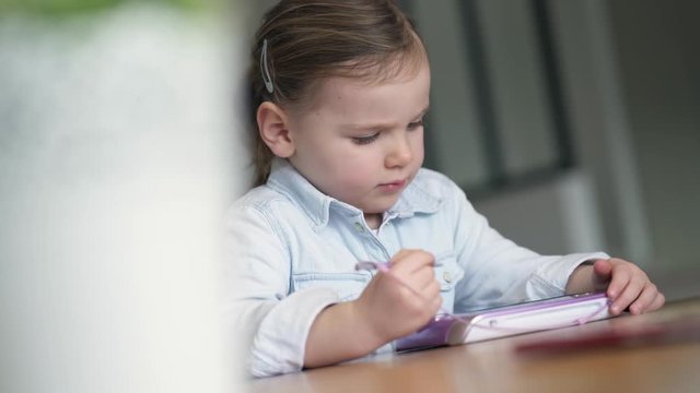 Adorable young girl playing alone on kid's tablet at home