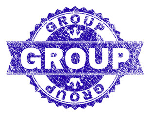 GROUP rosette stamp imprint with grunge texture. Designed with round rosette, ribbon and small crowns. Blue vector rubber print of GROUP text with grunge style.
