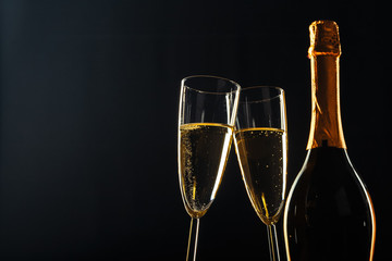 bottle of champagne and glasses over dark background