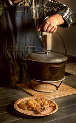 man is cooking roast. Portion of roast on a plate, the cook raises a cast-iron pot