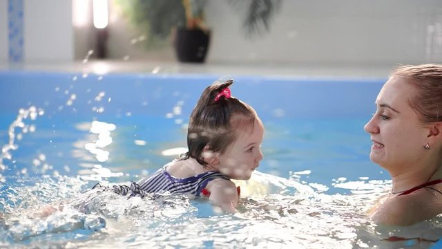 Happy smiling toddler is jumping and diving under the water in the swimming pool. An underwater shot. Slowmotion