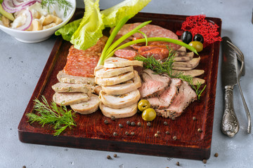 Assorted meat and sausage on a wooden board with mushrooms in the background