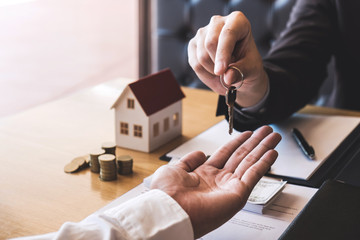 Estate agent giving house keys to client after signing agreement contract real estate with approved...