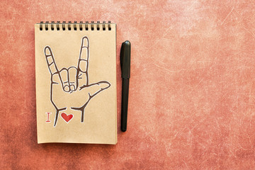 Notebook of Kraft paper, with a painted ASL (American sign language) symbol I Love you (ILY). Suitable for congratulations to the holiday Valentines day