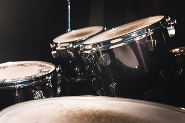 Fototapeta na wymiar Closeup view of a drum set in a dark studio. Black drum barrels with chrome trim. The concept of live performances
