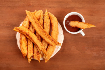 Traditional Spanish porras with hot chocolate, a typical Madrid Sunday breakfast, shot from above on a dark rustic wooden background with a place for text