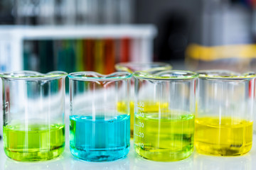 Lab glassware containing chemical liquid with laboratory background, science research and development concept 