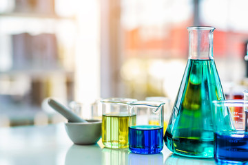 Lab glassware containing chemical liquid with laboratory background, science research and development concept 