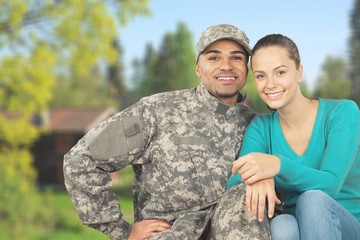 Smiling soldier with his wife standing against  background