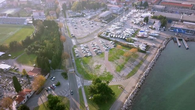 Aerial: Flying beside beautiful Isola in Adriatic with green socer field. Filming with drone on sunny winter day beside the sea.