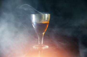 glass of cognac in the smoke on a black background