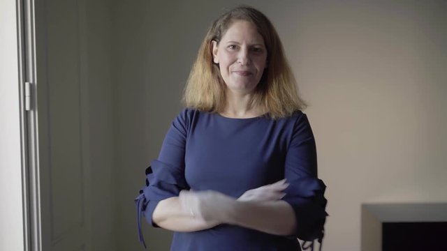 Video portrait of cheerful middle aged Caucasian woman in casual indoors. Smiling lady posing with arms crossed then with hands in pockets. Female portrait concept