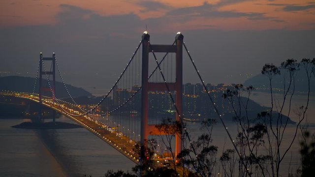 Hong Kong, China. Scenic evening cityscape of Tsing Ma Bridge and a car traffic on it. Built in 1997, Tsing Ma Bridge connects two Hong Kong islands - Tsin Yi and Ma Wan. Panning shot, 4K