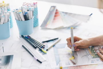 Close-up of the hand of a Interior designer working with an architectural plan with art tools and color palette
