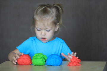 little girl playing with colorful play dough with great interest