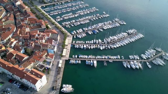Aerial: Flying beside beautiful Isola in Adriatic with marina full of boats. Filming with drone on sunny winter day beside the sea.