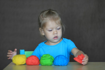 Fototapeta na wymiar little girl playing with colorful play dough with great interest